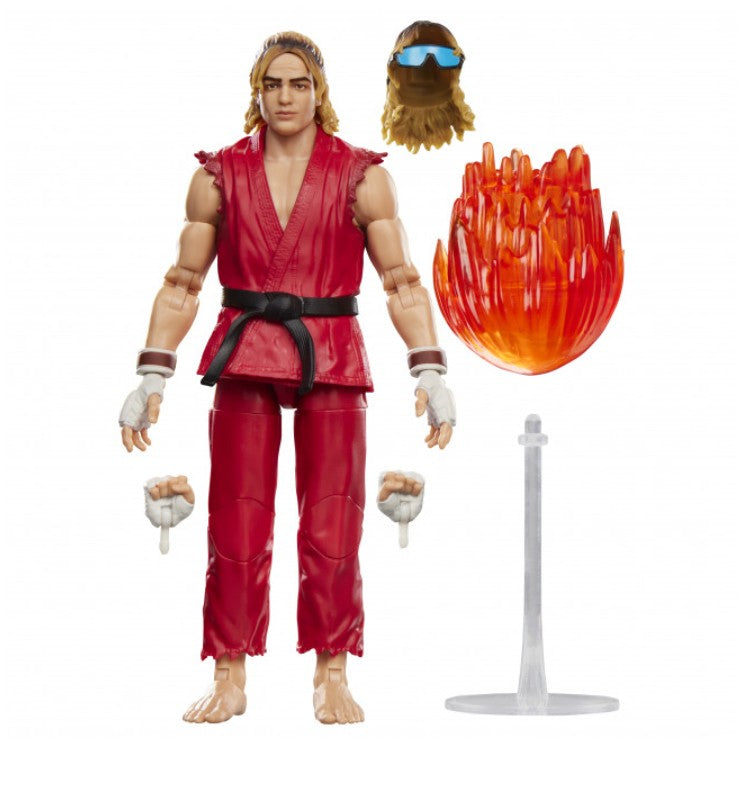 Hasbro Street Fighter Ken action figure with a black belt, shown with interchangeable hands, a beard accessory, and a translucent orange flame effect piece on a clear stand against a white background.